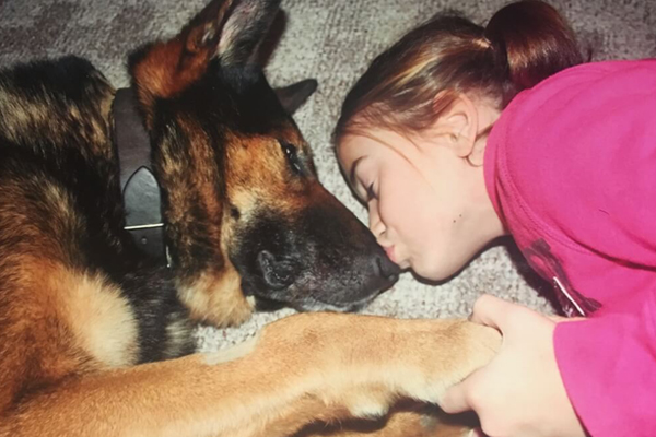 young girl kissing a dog on its snout